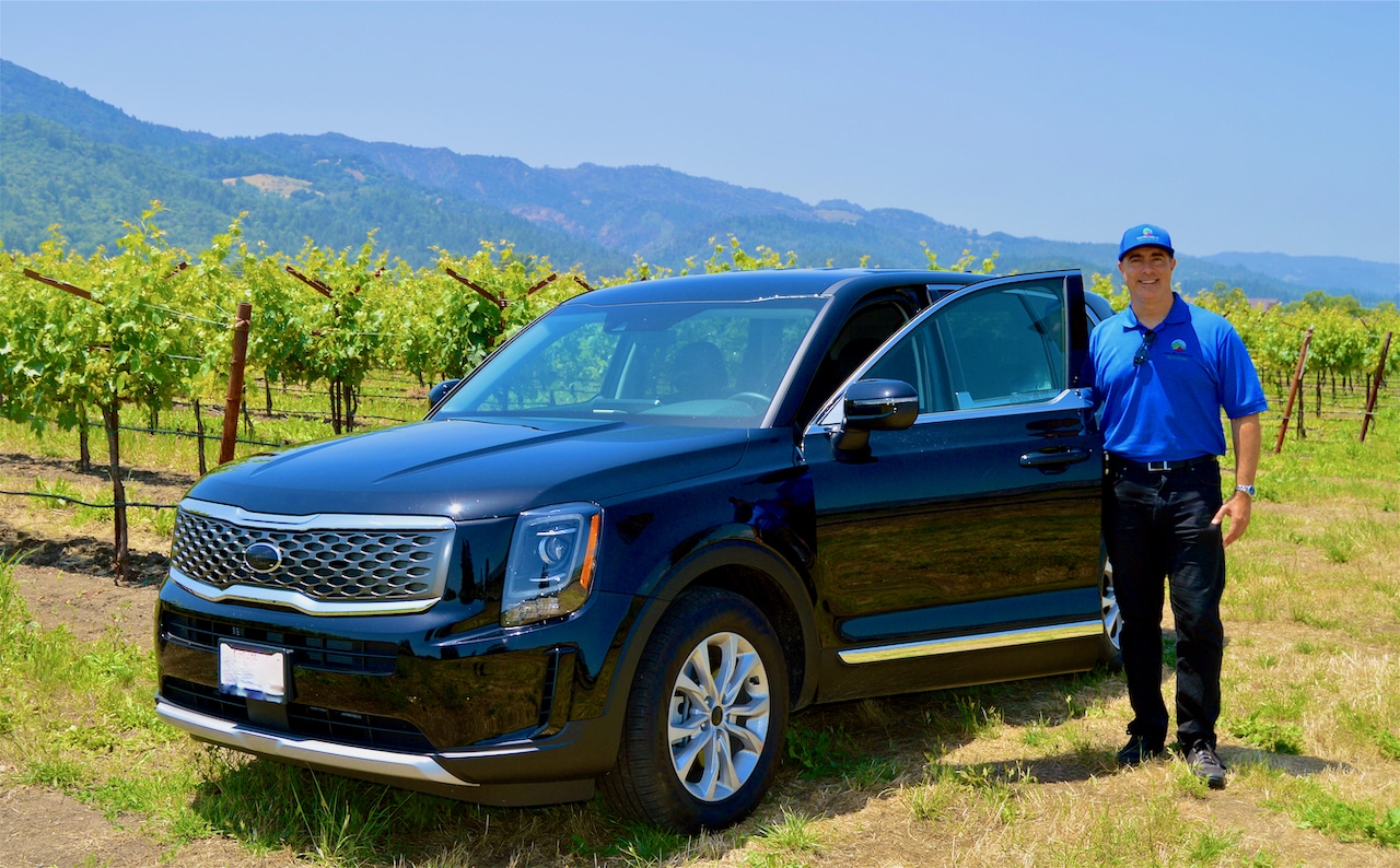 Active Wine Adventures black car parked near vineyards and driver Sorel Klein standing besides it