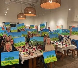 Guests holding up paintings at Paint & Sip event
