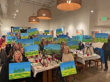 Guests holding up paintings at Paint & Sip event