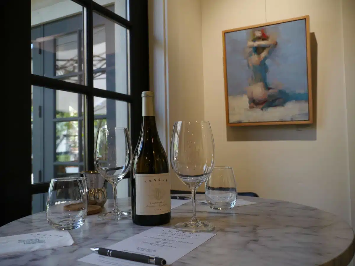 wine and wine glasses on table with art behind