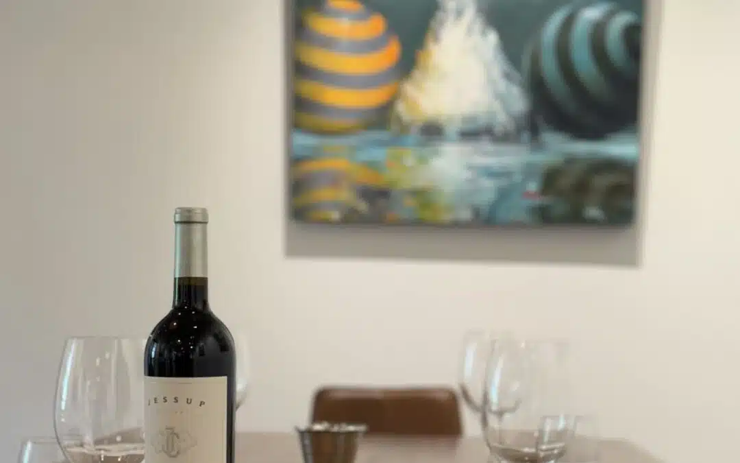 wine bottle on table with art on wall behind