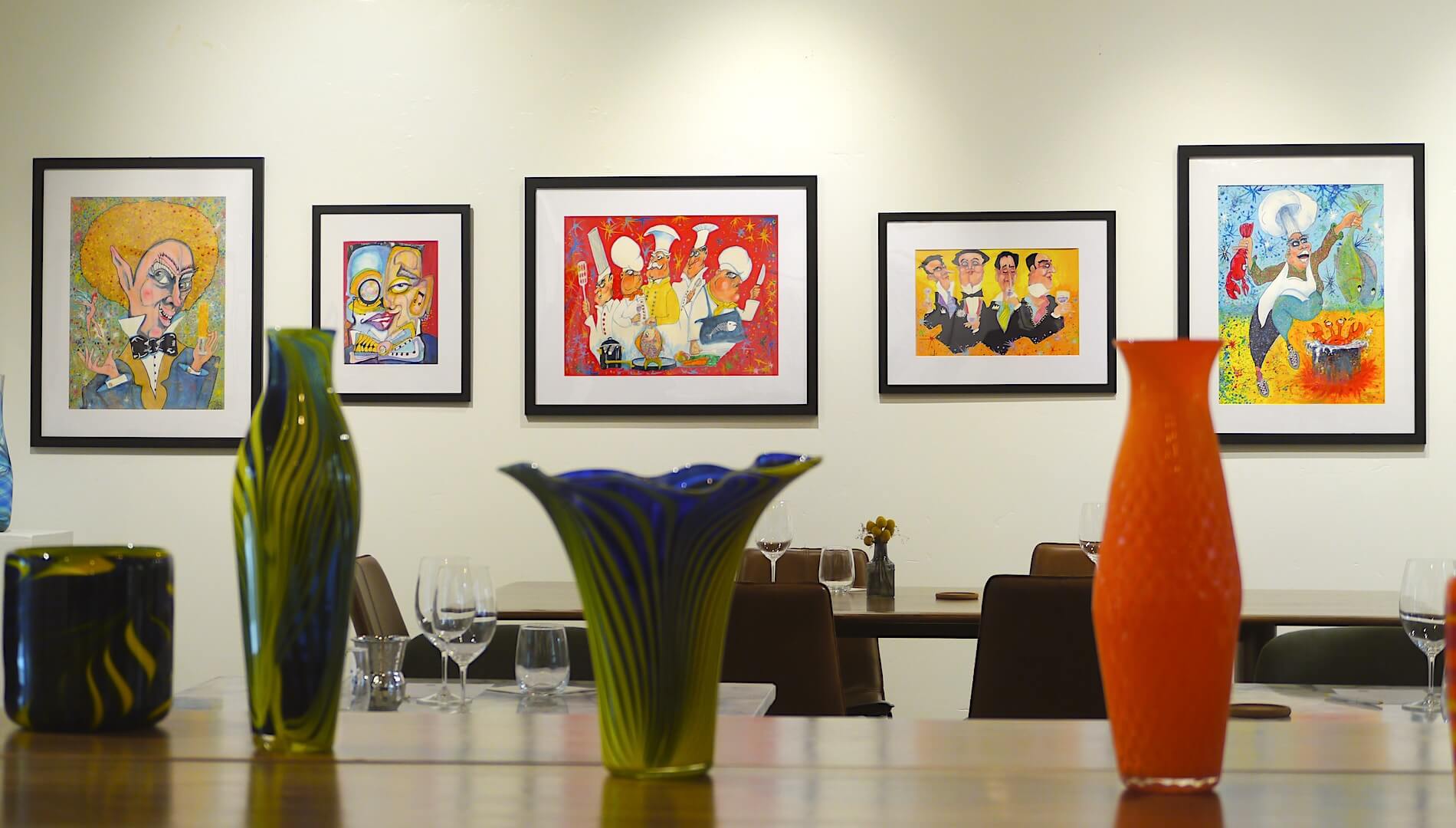 photo of glass pieces and framed illustrationsi n the back